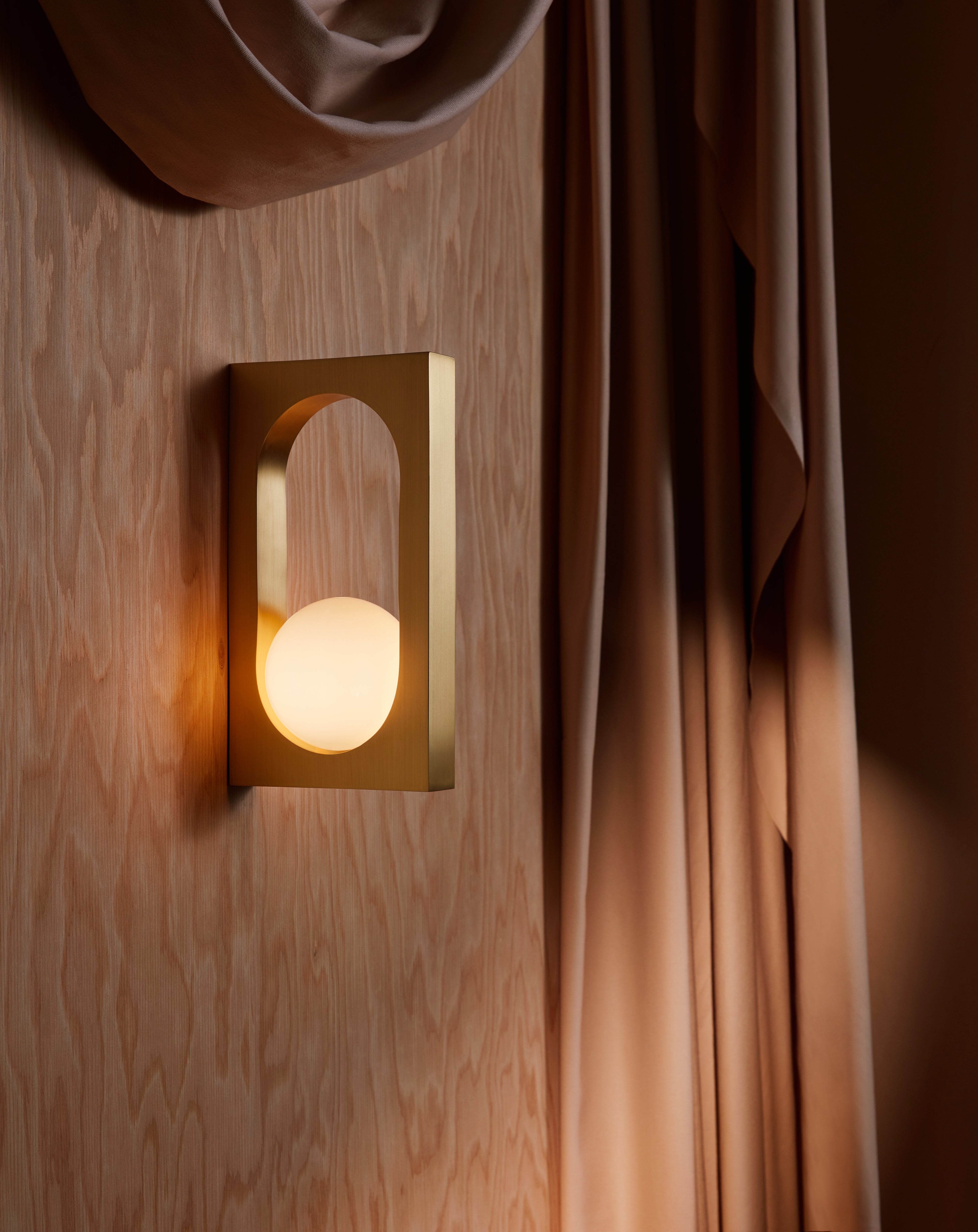 MYTHOS wall lamp with an opal shade and brass accents.