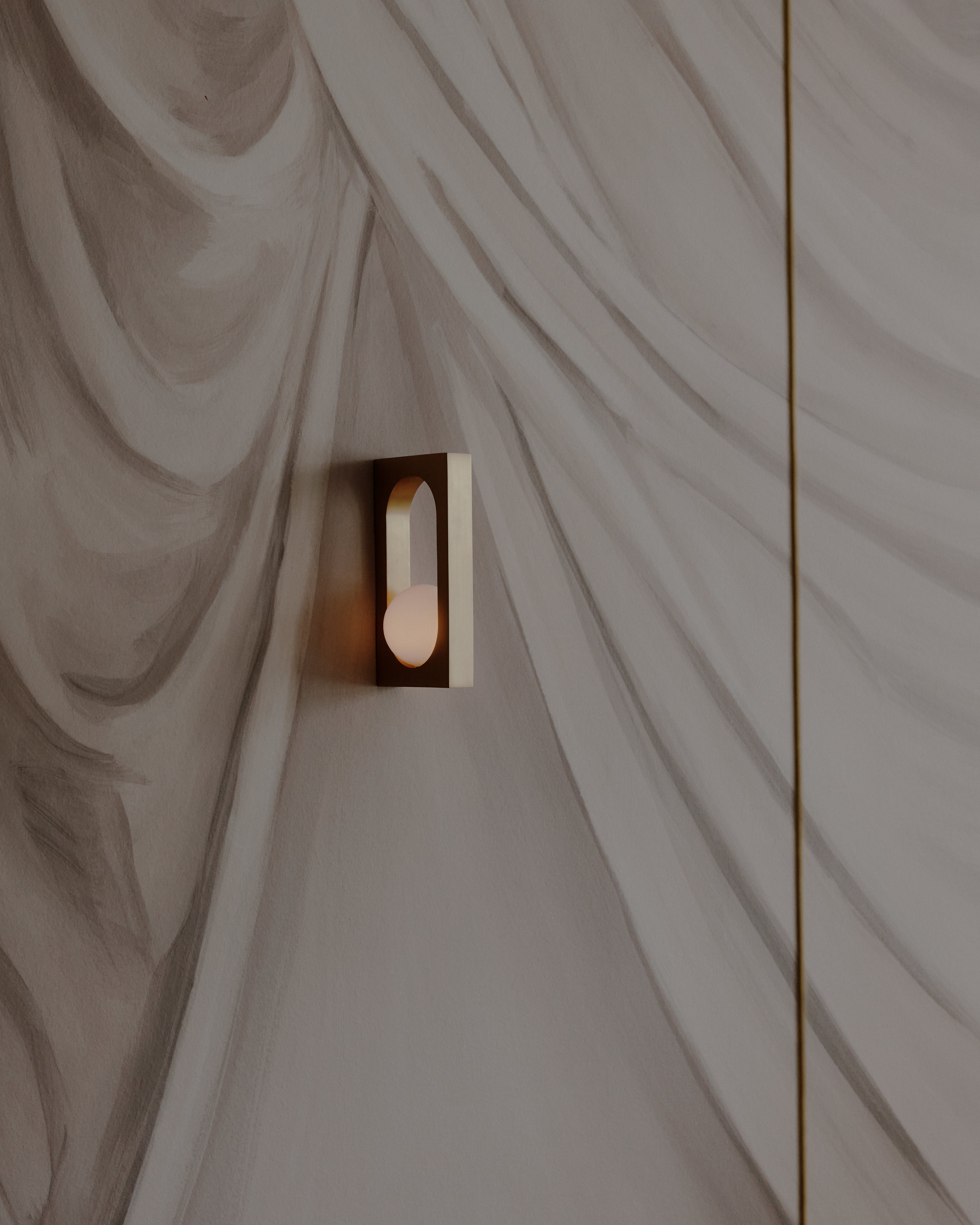 MYTHOS wall lamp with an opal shade and brass accents.
